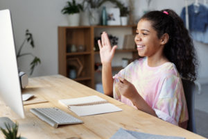 student in front of laptop raising hand